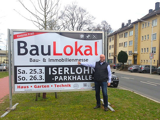 Veranstalter Dirk Bannenberg vor einem Großplakat zur BauLokal Baumesse in Iserlohn.